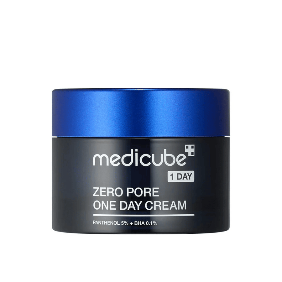 Medicube Zero Pore One Day Cream v elegantni črni posodici z modrim pokrovom. Vsebuje 5 % pantenola in 0,1 % BHA za zmanjšanje velikosti por in izboljšanje teksture kože. Popolno za vsakodnevno uporabo za bolj gladko in čistejšo kožo.