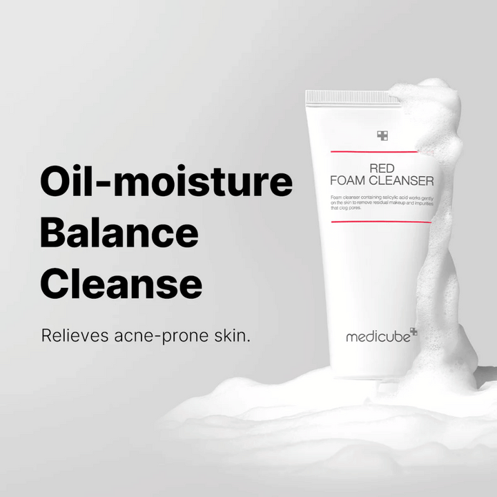 Tuba z Medicube Red Foam Cleanser stoji pokonci med penastim milom. Besedilo "Oil-moisture Balance Cleanse" se prikaže na levi strani, z opisom "Lajša kožo, nagnjeno k aknam" spodaj. Ozadje je svetlo sivo.