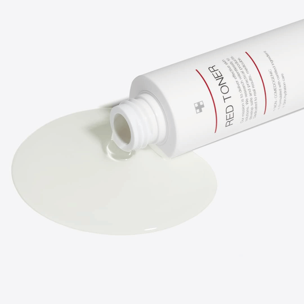 Odprta steklenička z medicube Red Toner, ki se izliva na belo površino - prikazuje lahko in tekočo konsistenco izdelka.