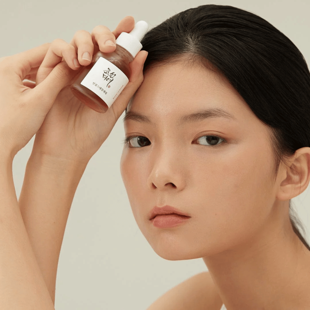 Model drži Beauty of Joseon Revive Serum ob licu – hranilen serum z ginsengom in snail mucin.