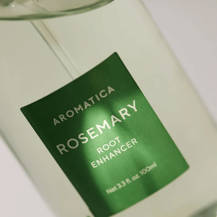 Detajlni posnetek etikete na AROMATICA Rosemary Root Enhancer. Zelena etiketa in prozorna steklenička poudarjata čist in minimalističen videz izdelka.
