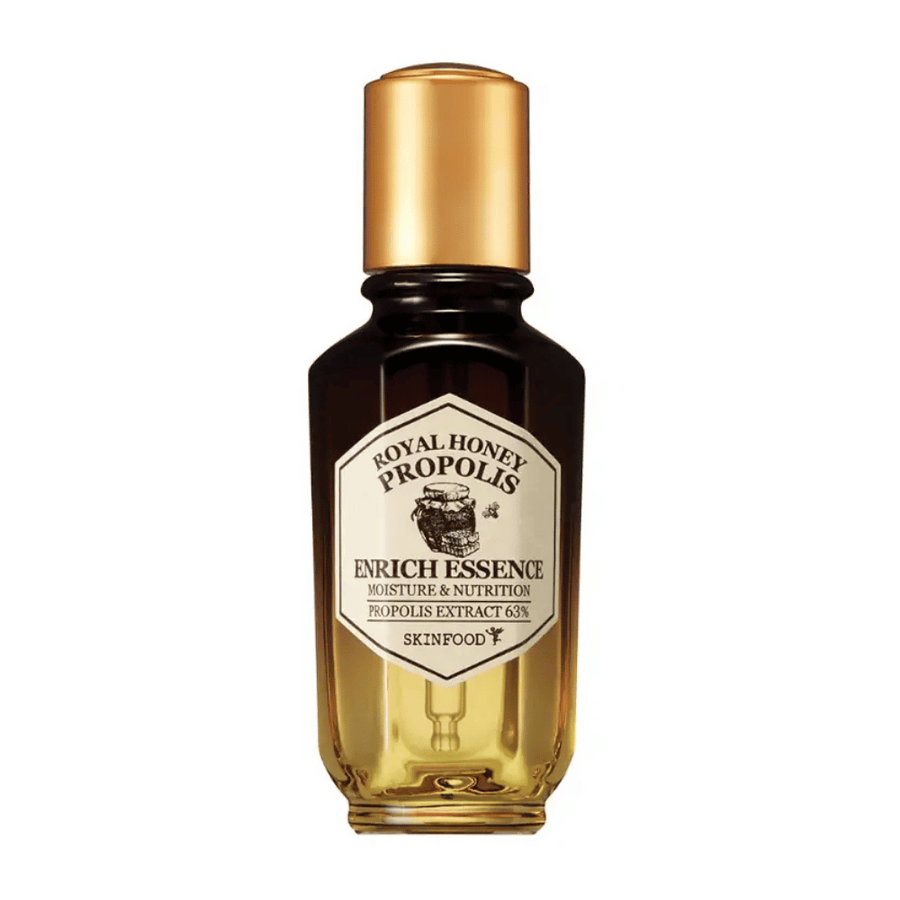 Slika steklenice iz stekla s temno tekočino in zlatim pokrovom. Na etiketi steklenice piše "Royal Honey Propolis Enrich Essence", sledi "Moisture & Nutrition" in "Propolis Extract 63%". Znamka "Skinfood" je vidna tudi na dnu etikete.