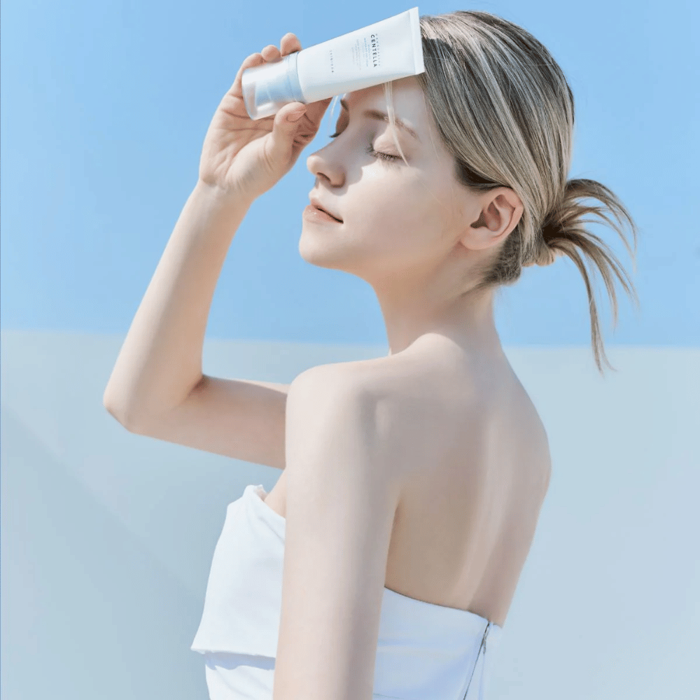 Ženska nanaša SKIN1004 Madagascar Centella Hyalu-Cica Water-Fit Sun Serum 50ml, da zaščiti obraz pred UV-žarki.