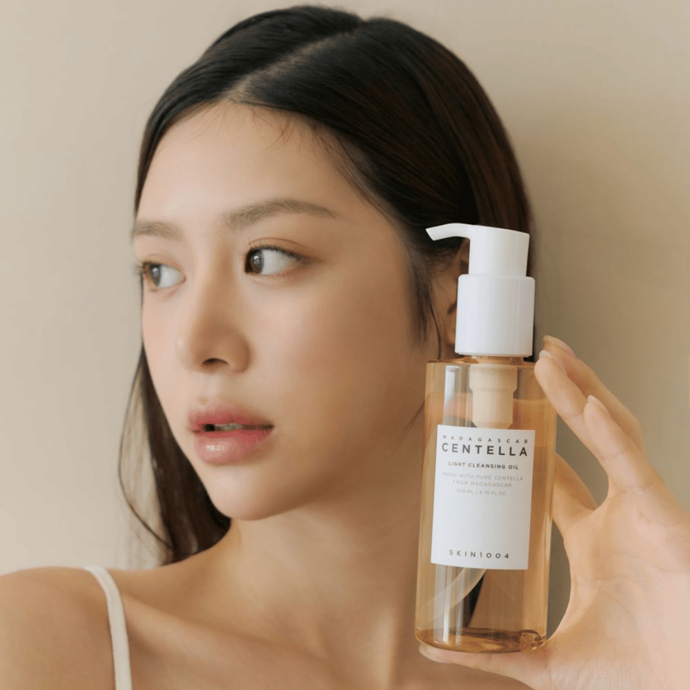 Ženska, ki drži steklenico SKIN1004 Madagascar Centella Light Cleansing Oil 200 ml čistilo za obraz.