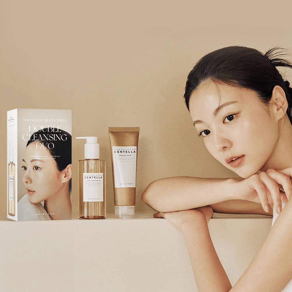 SKIN1004 Madagascar Centella Double Cleansing Duo Set s kartonom, oljno čiščenje, penasto čiščenje in model z navlaženo kožo na bež ozadju.