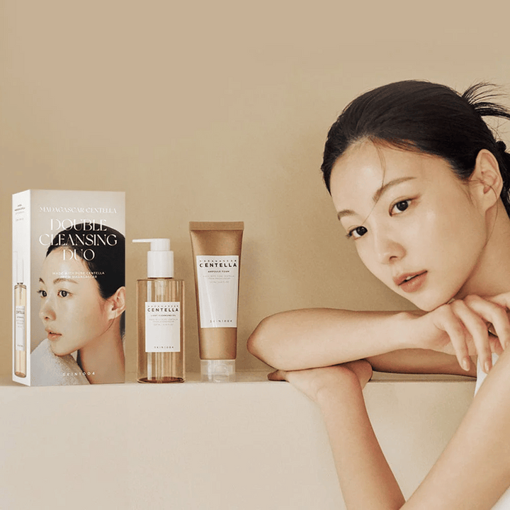 SKIN1004 Madagascar Centella Double Cleansing Duo Set s kartonom, oljno čiščenje, penasto čiščenje in model z navlaženo kožo na bež ozadju.