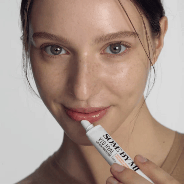 Ženska drži tubo V10 Hyal Lip Sun Protector SPF15 7ml balzama za ustnice za zaščito pred soncem in vlaženje, od SOME BY MI.