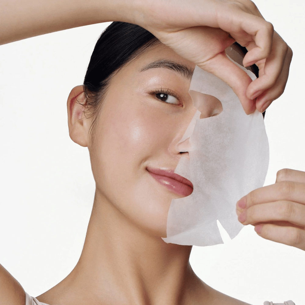 Ta slika prikazuje osebo, ki uporablja obrazno masko, natančneje "Galactomyces Glutathione Daily Mask" iz Some By Mi. Maska posvetli kožo in ji daje sijaj, hkrati pa neguje in globinsko vlaži kožo, zahvaljujoč sestavinam, kot sta glutation in vitamin C.