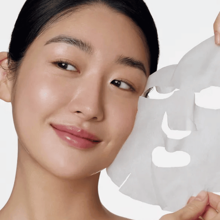 Slika prikazuje osebo, ki uporablja obrazno masko, natančneje "Retinol Intense Daily Mask" znamke Some By Mi. Maska je zasnovana za vsakodnevno uporabo in vsebuje retinol za izboljšanje teksture kože, zmanjšanje drobnih linij in zagotavljanje enakomernejšega tena kože.