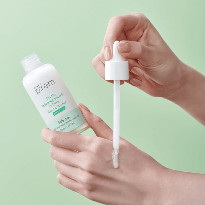 Roke držijo odprto stekleničko in pipeto Safe Me Relief Moisture Green Ampoule proti mehko zeleni podlagi.
