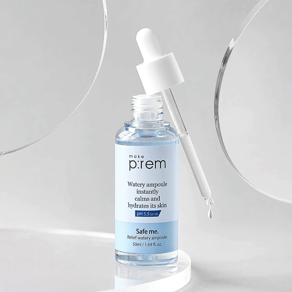 Prozorna modra steklenička Safe Me Relief Watery Ampoule s pipeto, kapljice vode, proti sivi podlagi in ogledalu.