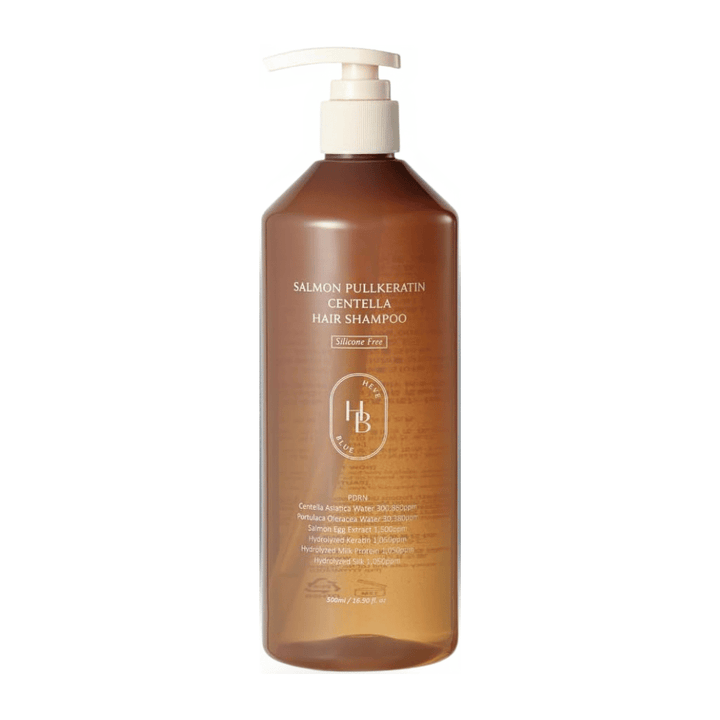 Heveblue Salmon Pullkeratin Centella Hair Shampoo v prozorni rjavi plastenki s potisno črpalko na svetlem ozadju. Šampon s centello, izvlečkom lososa in keratinom, ki pomaga čistiti in negovati lase.