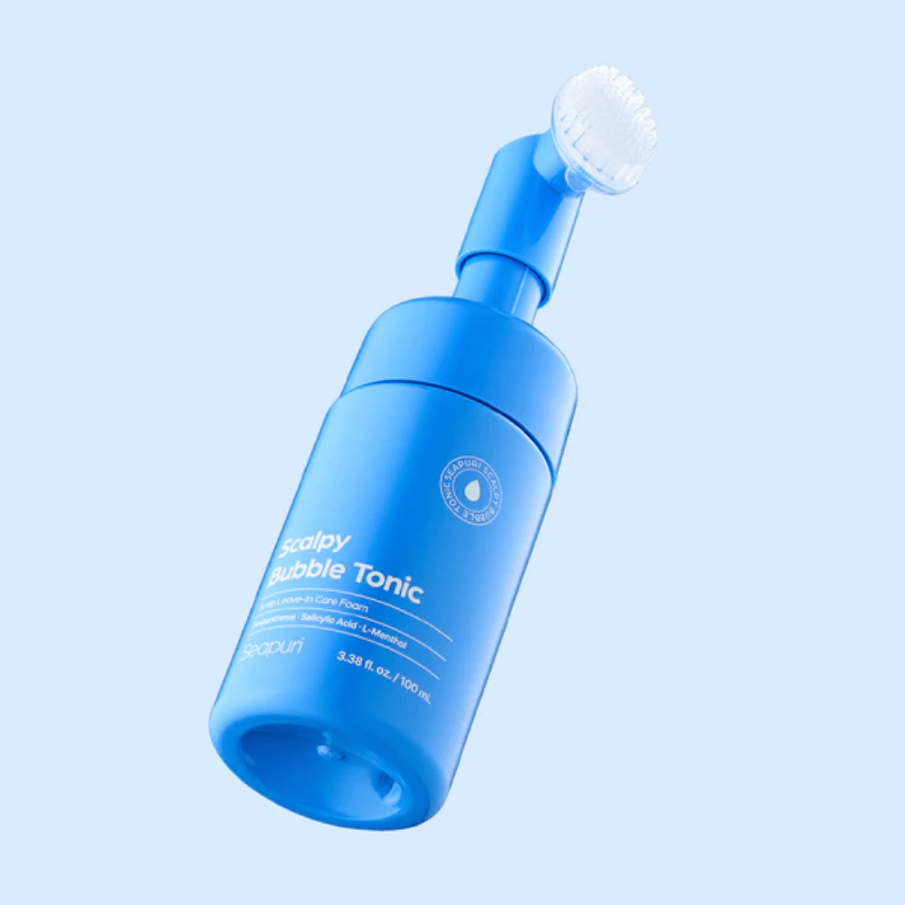 Elegantna produktna slika Seapuri Scalpy Bubble Tonic na svetlo modrem ozadju, ki poudarja sodoben dizajn in edinstven nastavek s krtačko za nego lasišča.