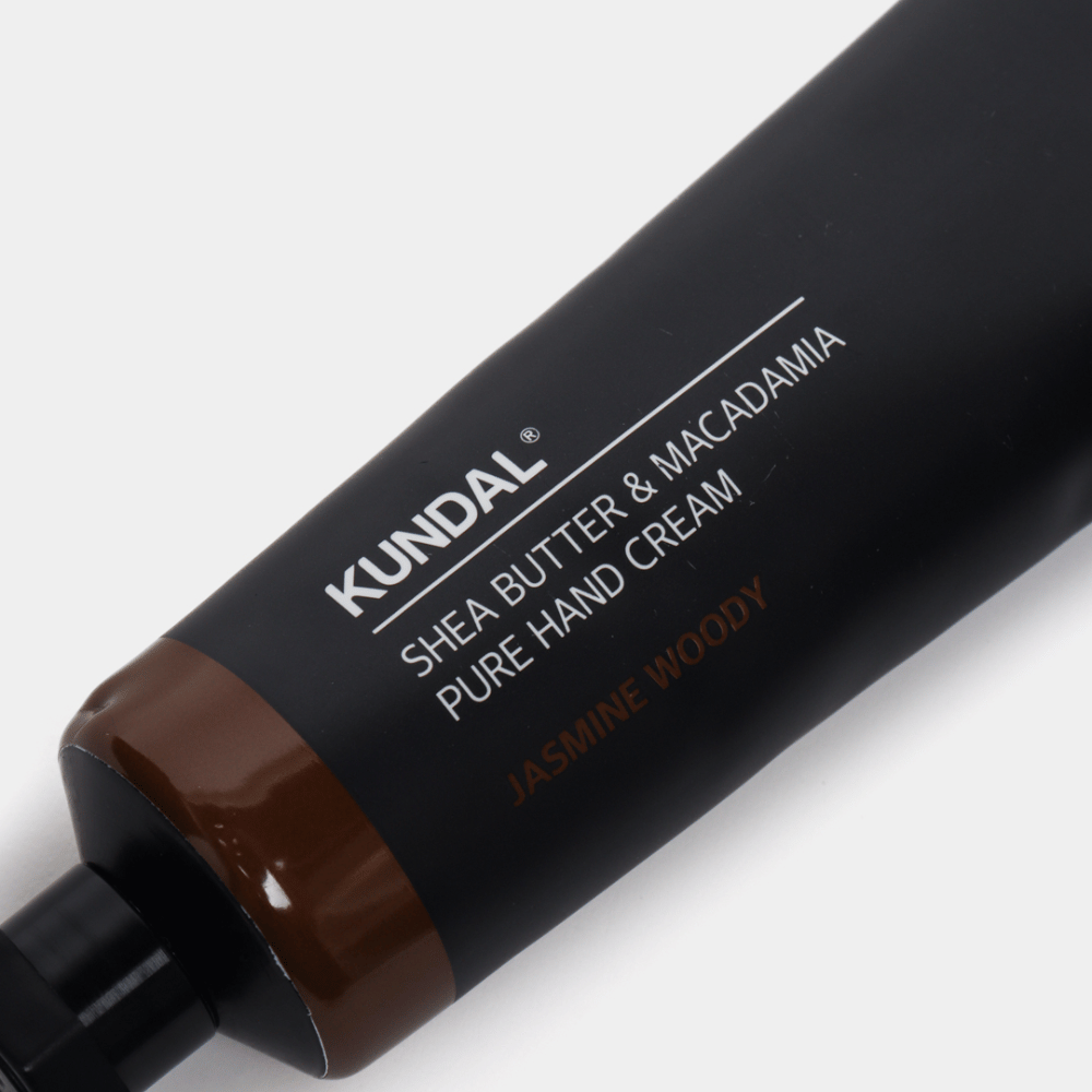 Povečava na KUNDAL Shea Butter & Macadamia Pure Hand Cream Jasmine Woody prikazuje elegantno embalažo in občutek premium kreme za roke.