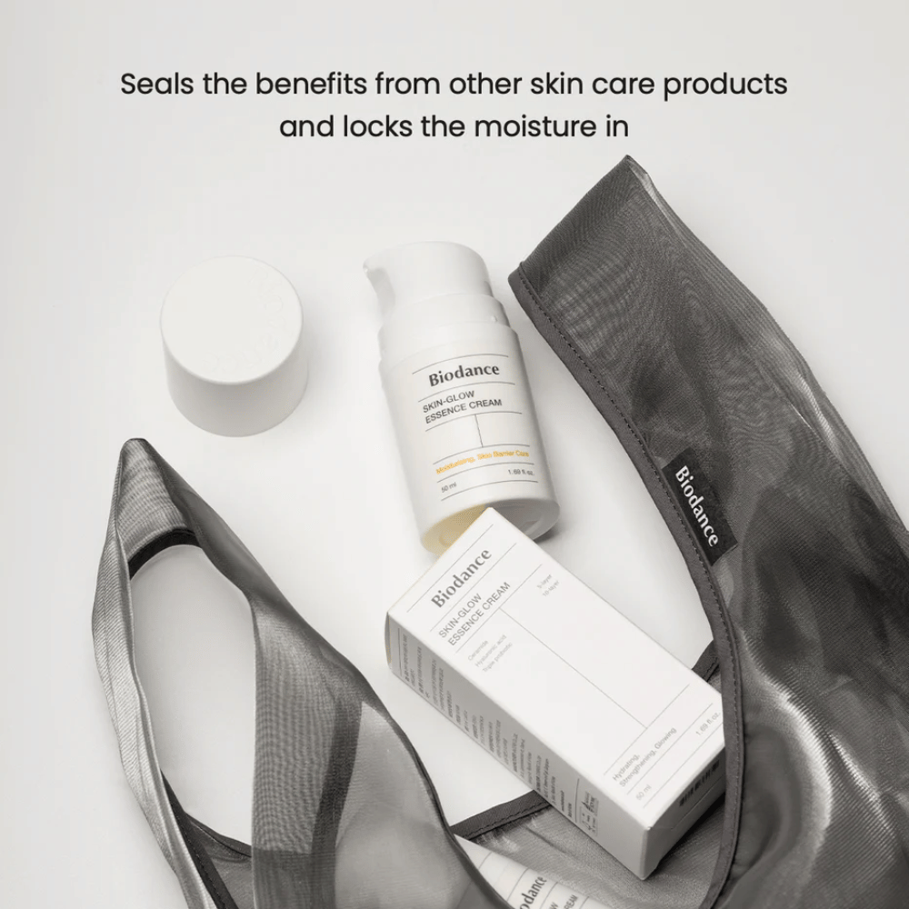 Biodance Skin-Glow Essence Cream stoji v ospredju skupaj z embalažo izdelka in črno prozorno toaletno torbico, z besedilom nad njo, ki poudarja sposobnost kreme, da zadrži vlago in okrepi učinek drugih izdelkov za nego kože.