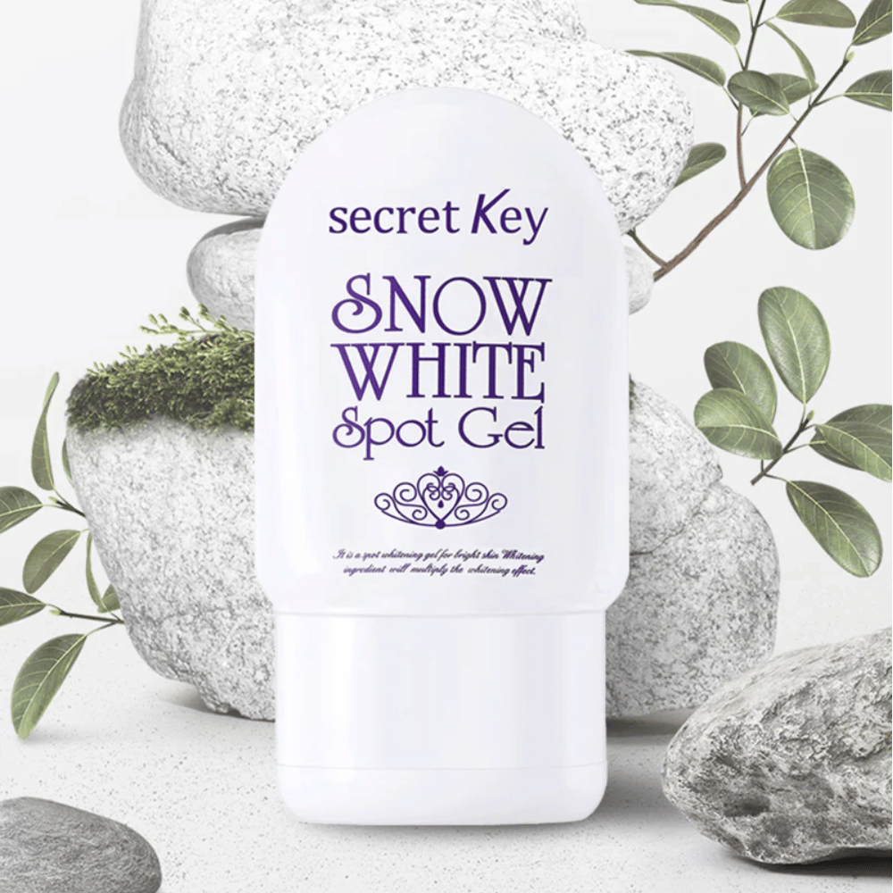 Secret Key Snow White Spot Gel fotografiran ob kamnih in zelenih listih.