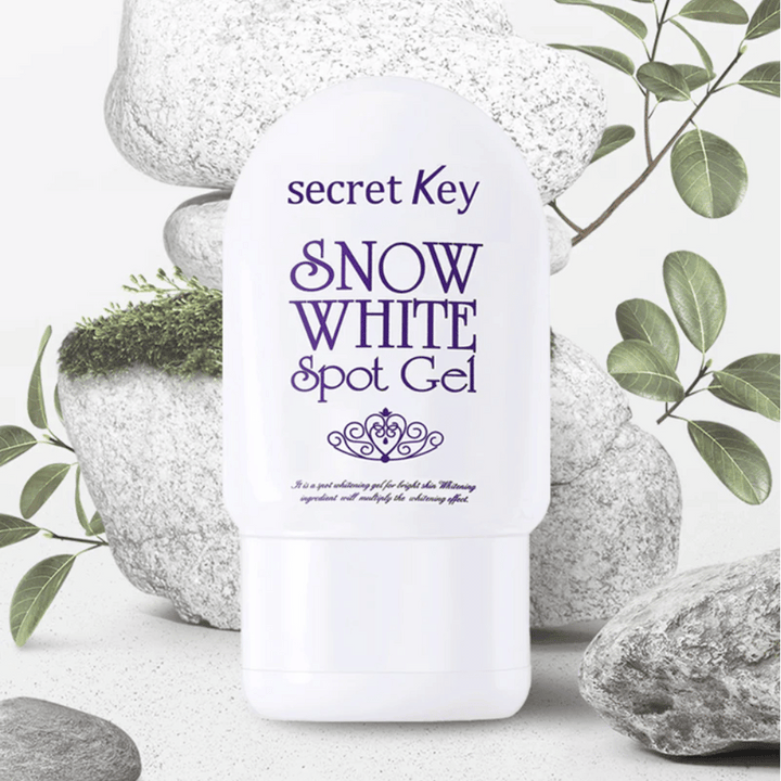 Secret Key Snow White Spot Gel fotografiran ob kamnih in zelenih listih.