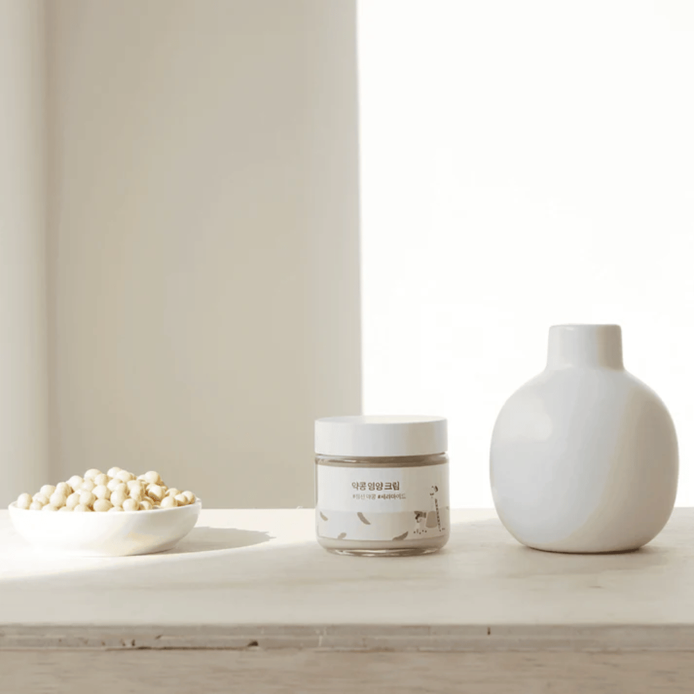Mixsoon Soybean Nourishing Cream stoji na leseni mizi poleg vaze in sojinih zrn. Minimalistična, vlažilna krema z naravnimi sestavinami.