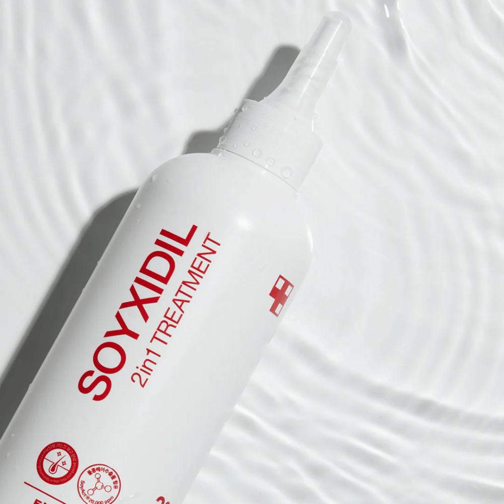 Steklenica Medicube Soyxidil 2in1 Treatment leži na valoviti vodni površini, kar simbolizira vlažilno in osvežilno nego.