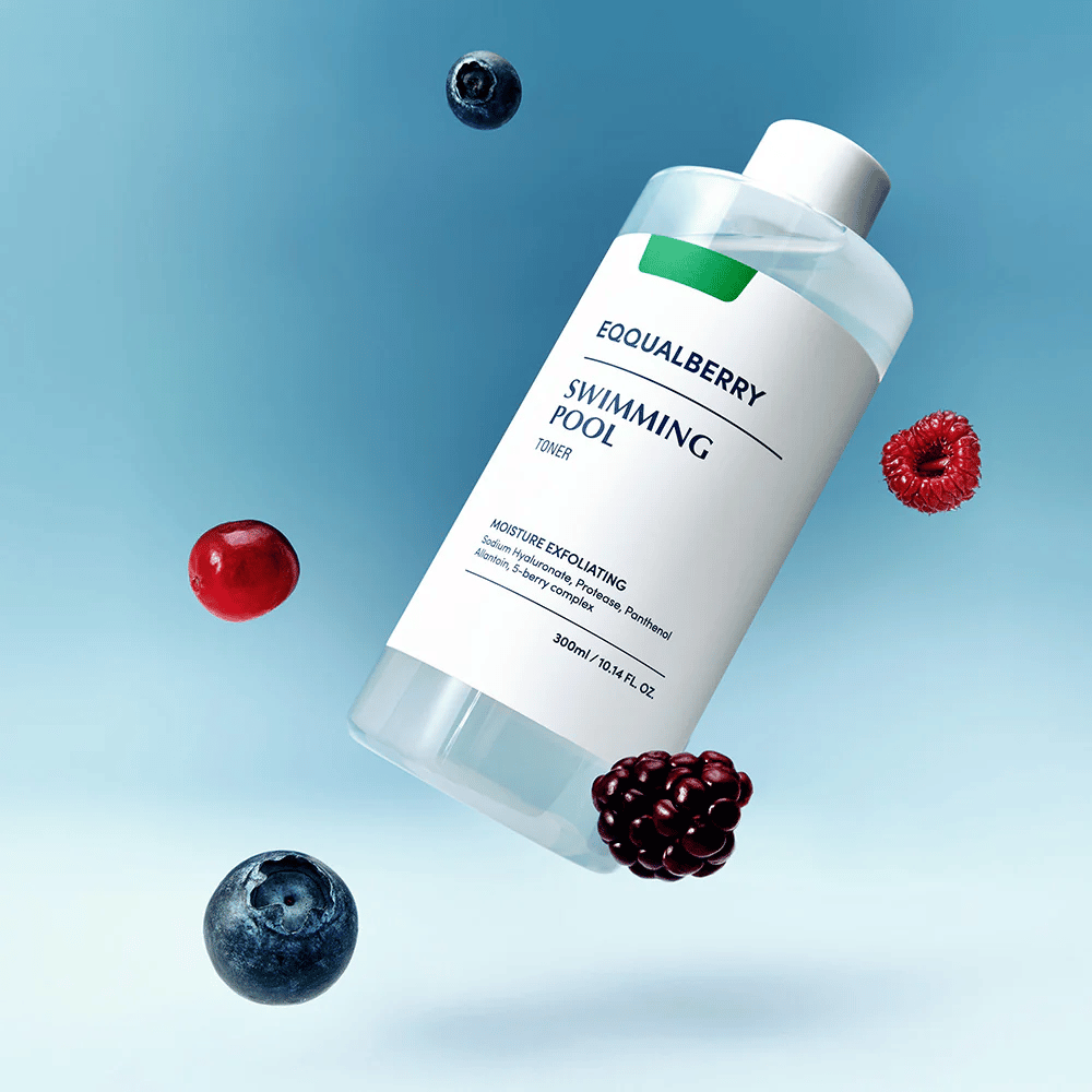 Equalberry Swimming Pool Toner v elegantni steklenički lebdi proti modremu ozadju, obdan s svežimi jagodami, kot so borovnice, maline in robide.