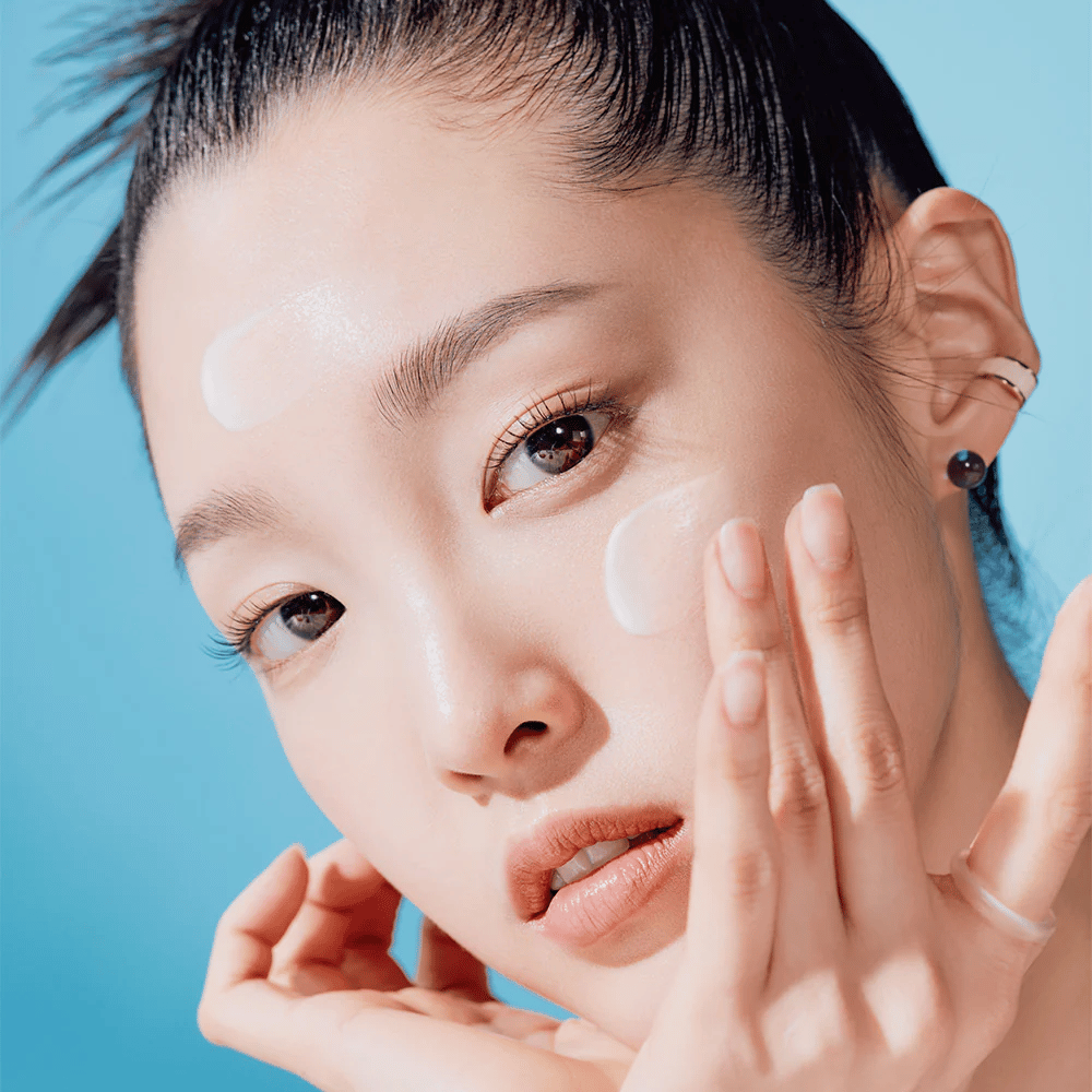 Ženska pozira z rokami na obrazu v kampanji za naravno nego kože TOCOBO Bio Watery Sun Cream SPF50+ PA++++ 50ml.