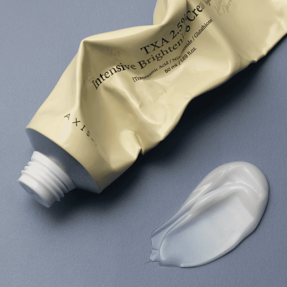 Produktna slika s tubo in kapljico kreme ob njej za prikaz mehke, kremaste teksture in vlažilne formule. Poudarek je na glow učinku in enakomernem nanosu.