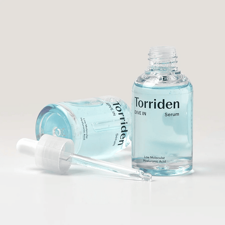Steklenica Torriden DIVE-IN Low Molecule Hyaluronic Acid Serum 50ml poleg steklenice vode, ki poudarja hialuronski serum in vlaženje.