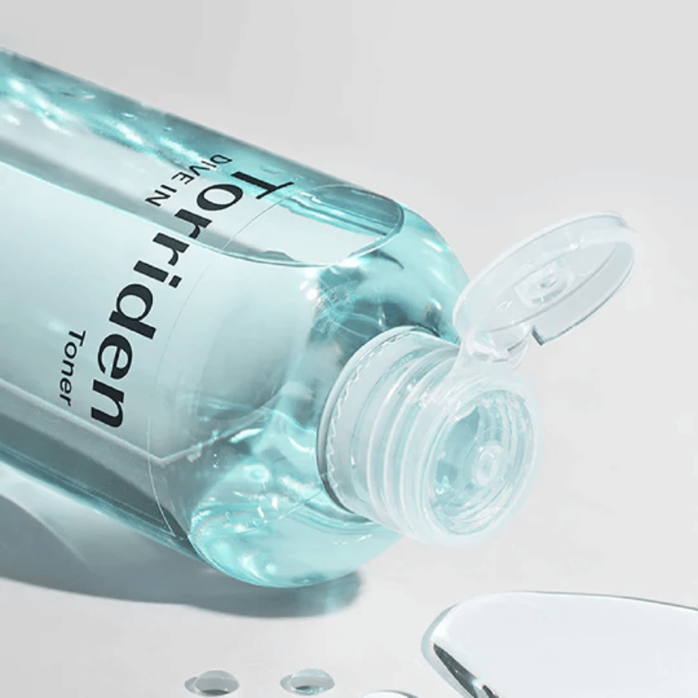 Steklenica DIVE-IN Low Molecule Hyaluronic Acid Toner 300ml poleg kozarca vode, promovira Torriden in vlaženje.