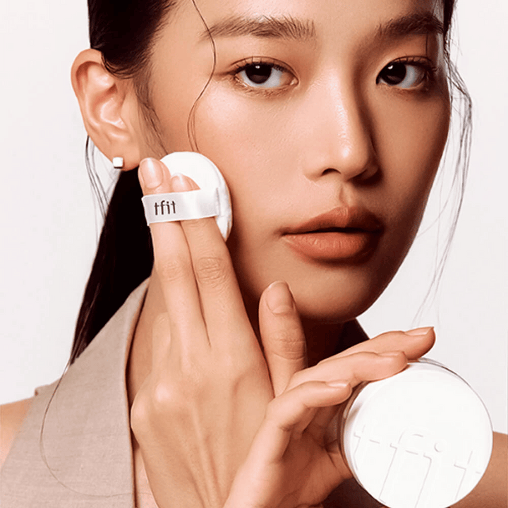 Ženska nanaša TFIT Translucent Set Finishing Powder #02 Skin Beige s puffom, drži belo škatlico pudra z logotipom TFIT.