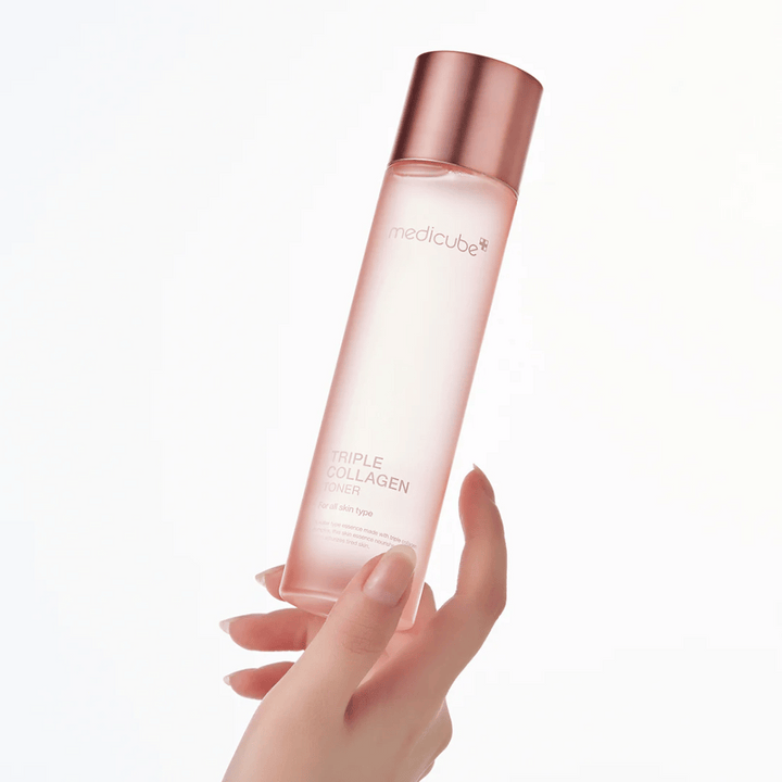 Roka, ki drži roza stekleničko Medicube Triple Collagen Toner 4.0, vlažilni in učvrstitveni tonik za vse tipe kože.