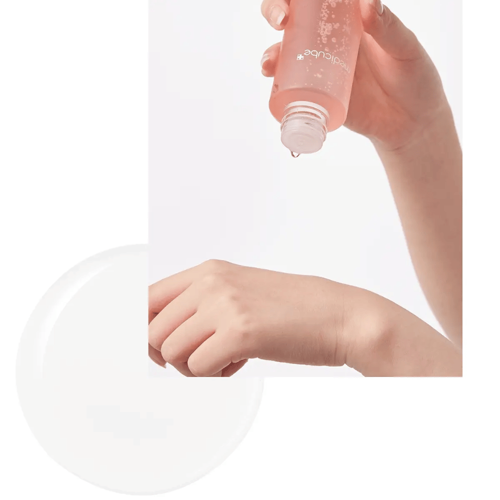 Roka, ki nanese Medicube Triple Collagen Toner 4.0 iz roza stekleničke na kožo, prikazuje vlažilno teksturo.
