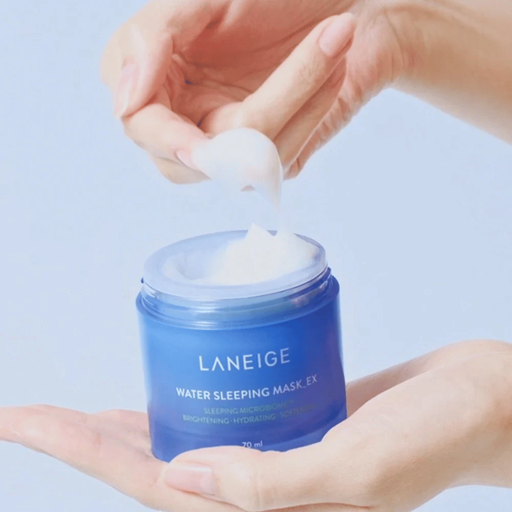 Roka zajema LANEIGE Water Sleeping Mask iz modre posode, s poudarkom na gelasti konsistenci na svetlo modri podlagi.