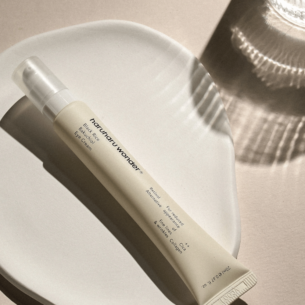 HaruHaru Wonder Black Rice Bakuchiol Eye Cream 20 ml – krema za oči s črnim rižem, bakuchiolom in kolagenom, ki zmanjšuje drobne linije in gube, postavljena na keramični krožnik v mehki svetlobi.