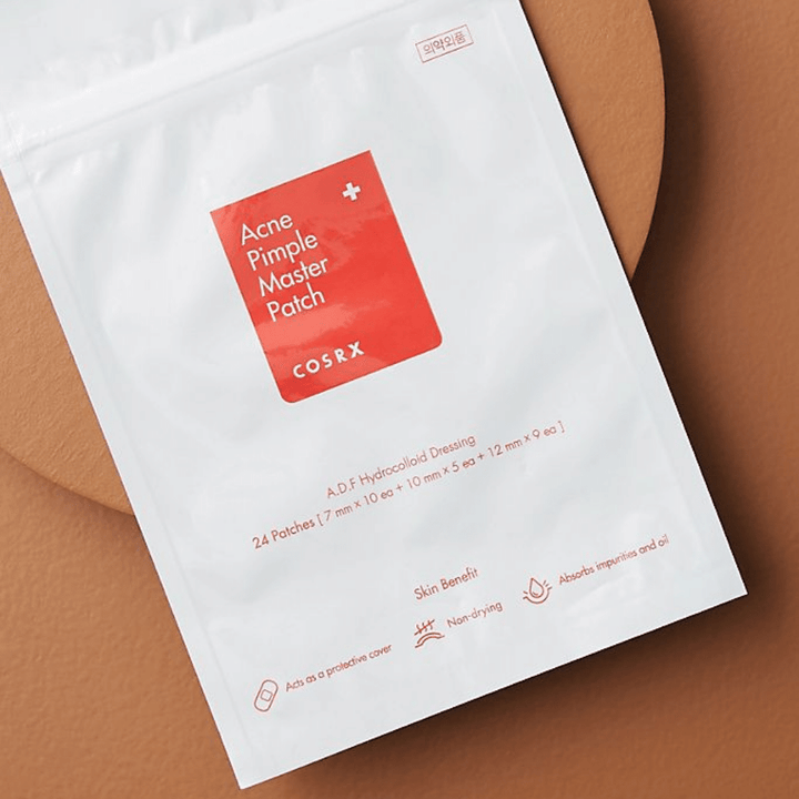 Paket COSRX Acne Pimple Master Patch (1 paket x 24 obližev) na rjavi podlagi, s hidrocoloido tehnologijo za zdravljenje aken in mozoljev.