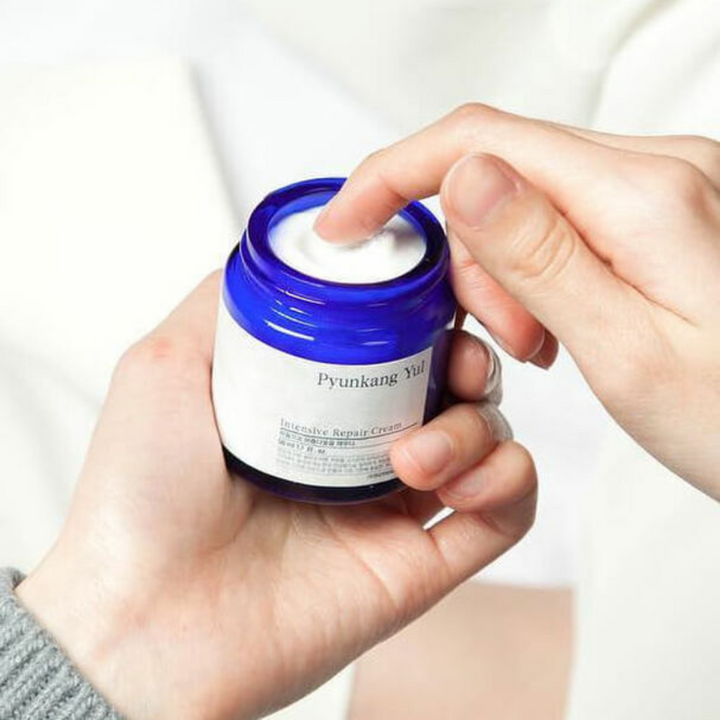 Oseba drži kozarec Pyunkang Yul Intensive Repair Cream 50ml.