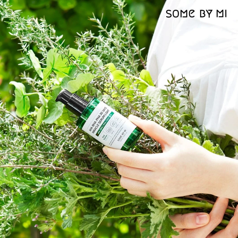 Ženska, ki drži šopek zelišč v rokah, da prepreči pigmentne madeže in akne s pomočjo AHA, BHA, PHA 30 Days Miracle Serum Light 50ml od SOME BY MI.