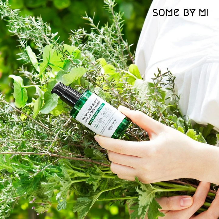 Ženska, ki drži šopek zelišč v rokah, da prepreči pigmentne madeže in akne s pomočjo AHA, BHA, PHA 30 Days Miracle Serum Light 50ml od SOME BY MI.