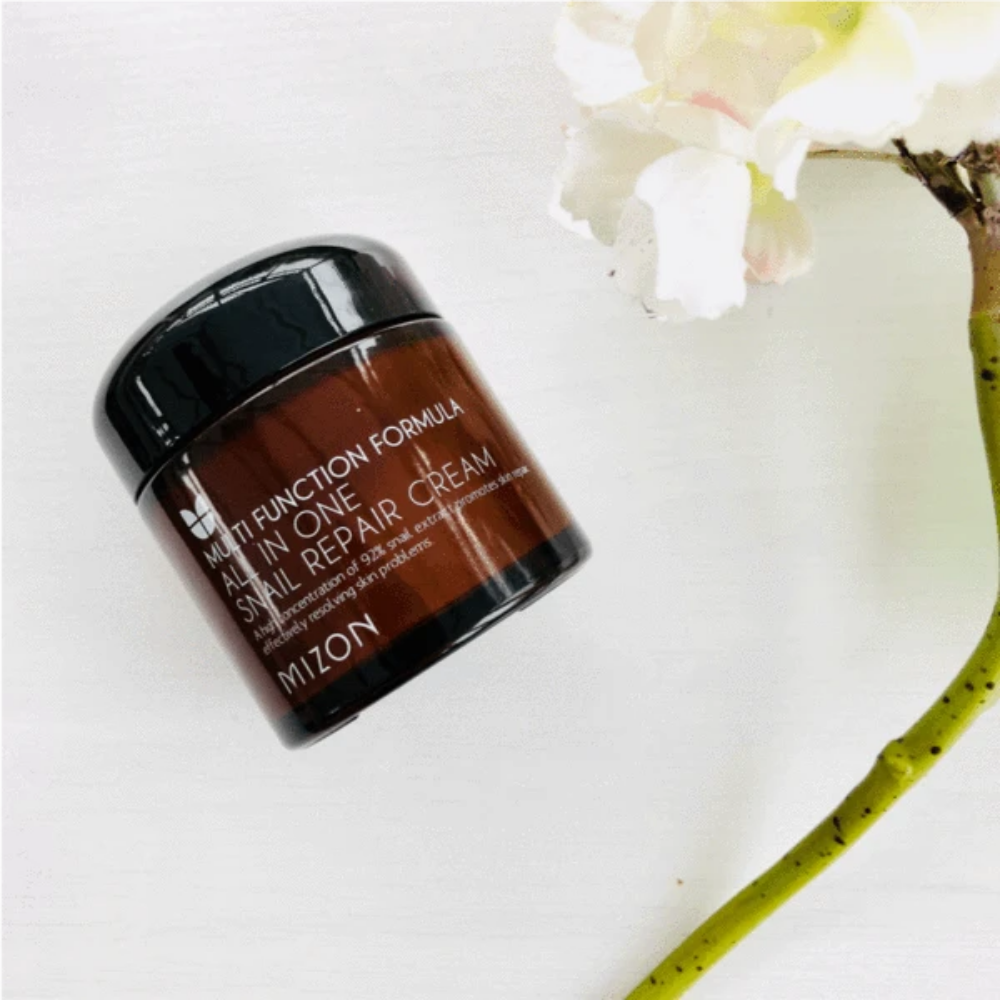 Lonček MIZON All In One Snail Repair Cream 75ml poleg rože.