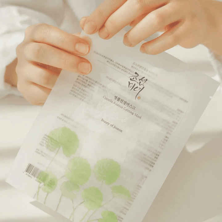 Oseba, ki drži list papirja z Beauty of Joseon Centella Asiatica Calming Mask 1 kos na njem.