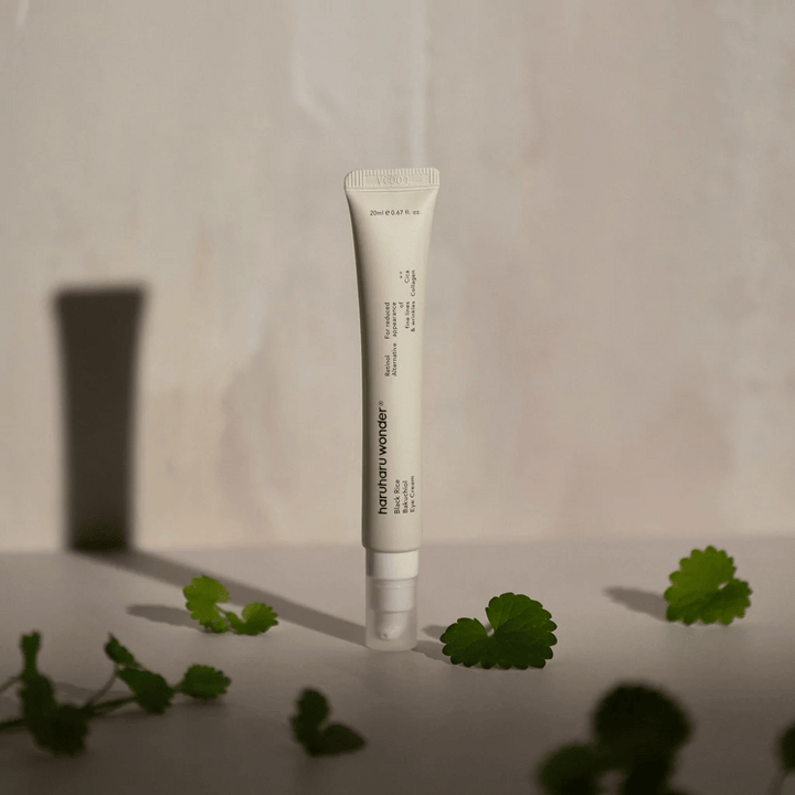 Ena tuba Haruharu Wonder Black Rice Bakuchiol Eye Cream 20ml obdana z zelenimi listi, osredotočena na vidnost gub in drobnih linij.