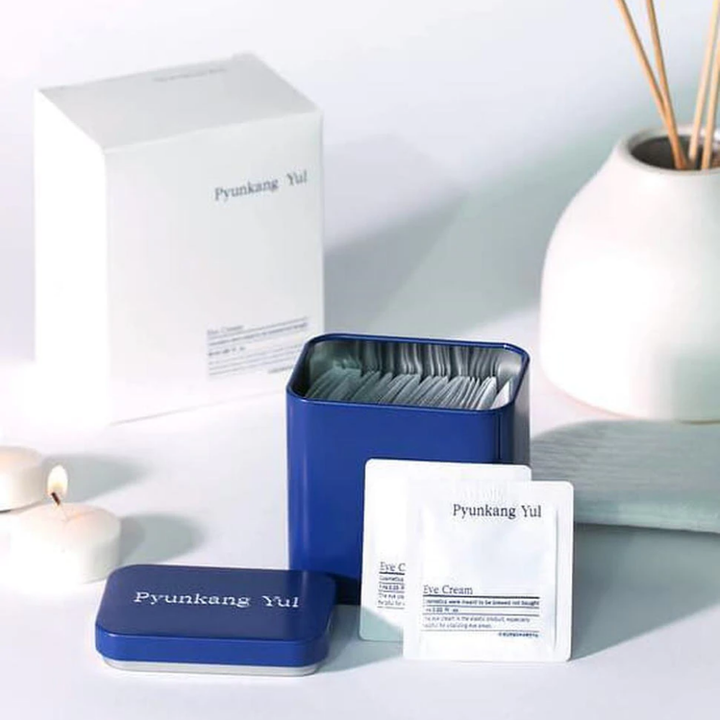 Bela škatla z modrim pokrovom in Pyunkang Yul Eye Cream 1ml x 50 kos poleg.