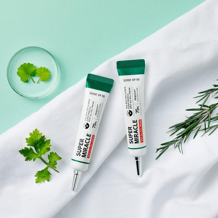 Dve tubi SOME BY MI-jeve AHA, BHA, PHA 14 Days Super Miracle Spot All Kill Cream 30 ml kreme za oči, ki ležita na beli tkanini, nasičeni s Truecico.