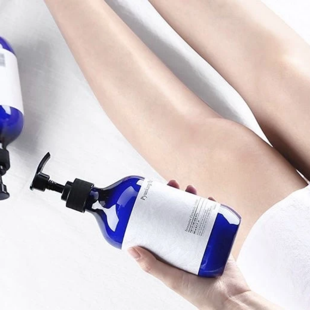 Ženska, ki drži steklenico Pyunkang Yul Intensive Ceramide Lotion 500ml poleg svojih nog.