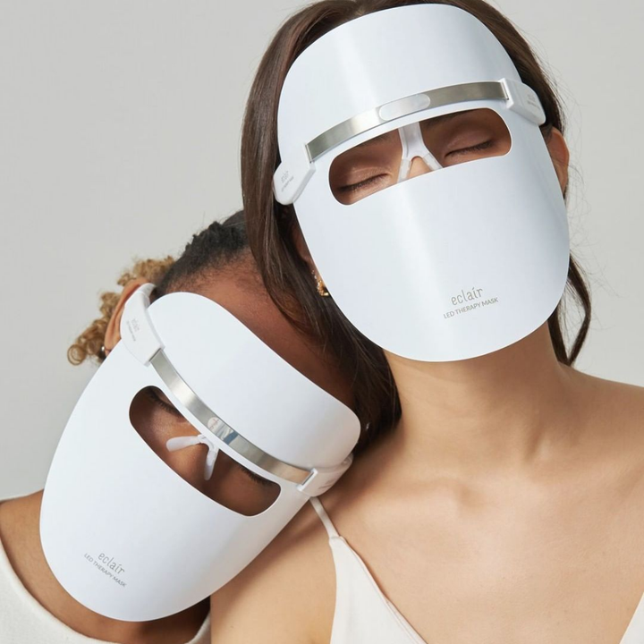 Dve ženski, ki nosita bele maske, demonstrirata ECLAIR LED Therapy Mask za izboljšanje tona kože.
