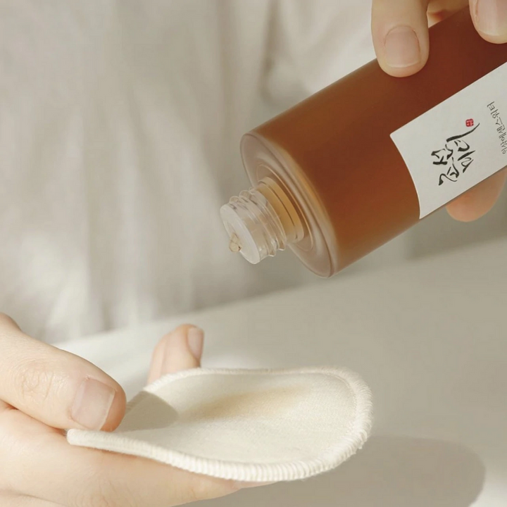 Oseba, ki vliva Beauty of Joseon Ginseng Essence Water 150ml na krpo za boj proti suhi koži in zmanjšanje proizvodnje sebuma.