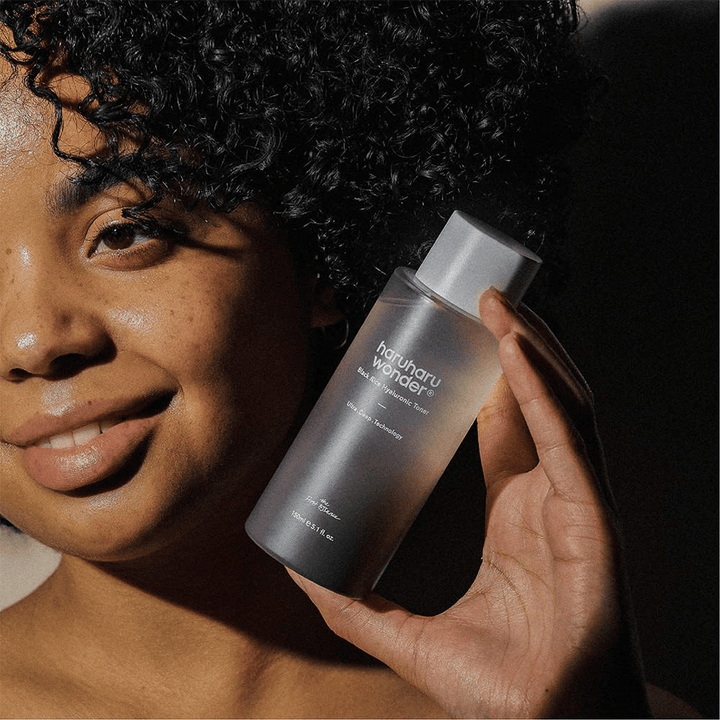 Ženska, ki drži steklenico Haruharu Wonder Black Rice Hyaluronic Toner Original 150ml.