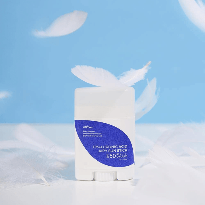 Isntree Hyaluronic Acid Airy Sun Stick z SPF 50+ in hialuronsko kislino, okrašena z belimi peresi.