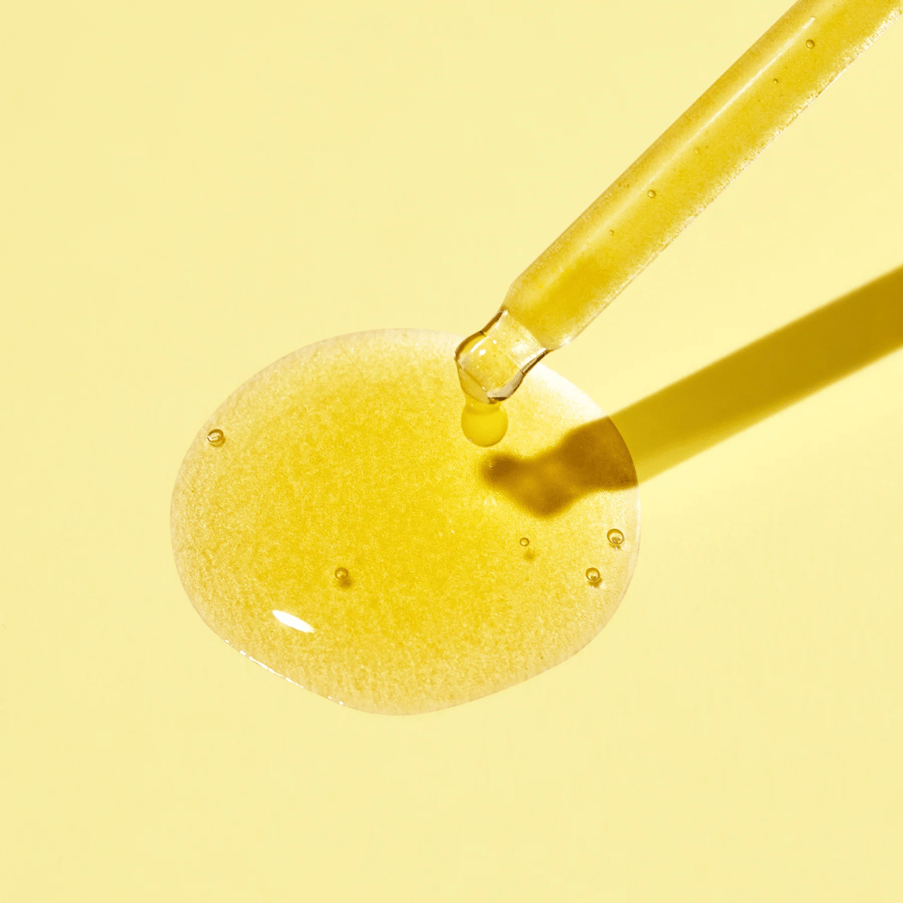 Kapljica tekočine na rumeni podlagi, z MISSHA Vita C Plus Spot Correcting & Firming Ampoule.