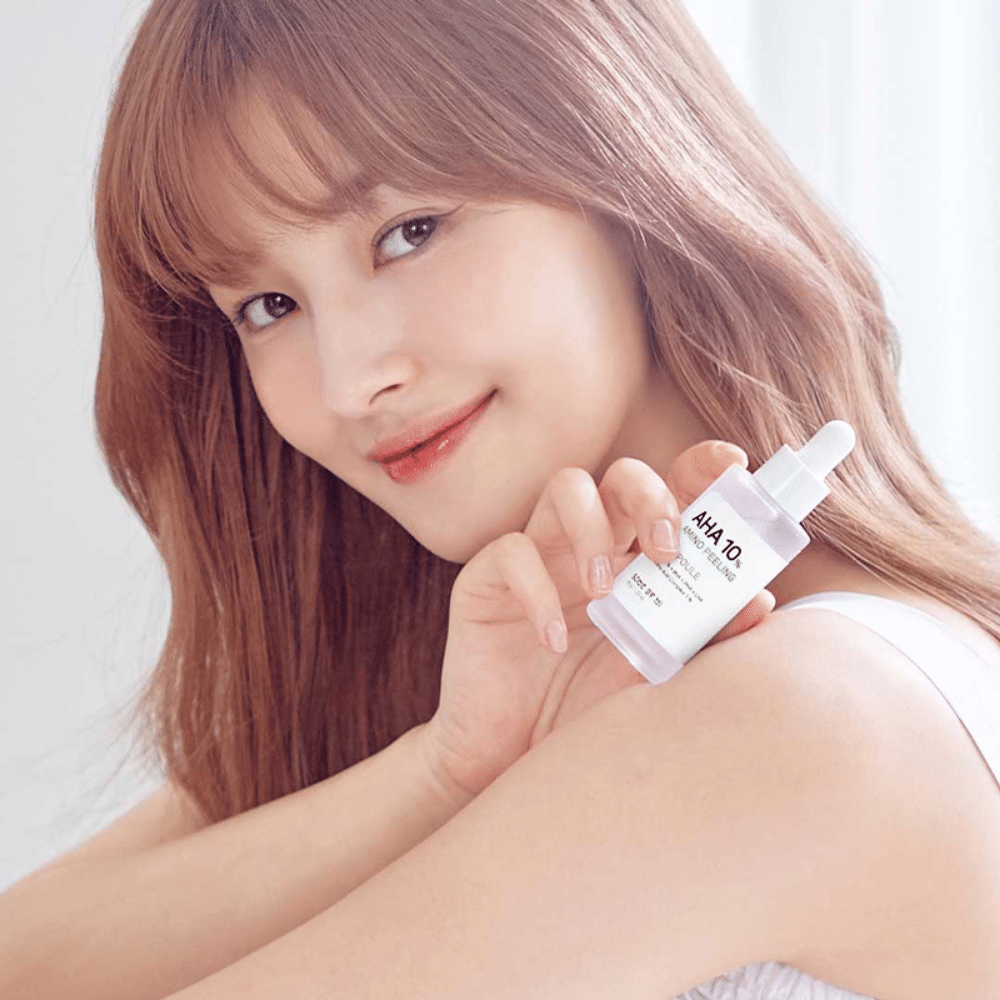Mlada ženska, ki drži stekleničko SOME BY MI AHA 10% Amino Peeling Ampoule 35g, ki vlaži kožo.